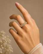 Hand wearing a gold ring with a blurred background